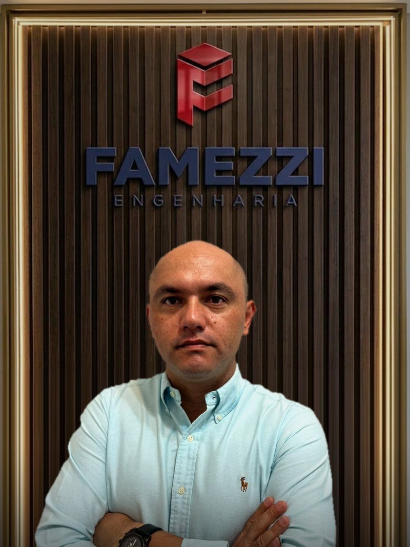 Fábio de Melo Silva, engenheiro civil em Mogi das Cruzes, em frente à parede com a logo da FAMEZZI Engenharia